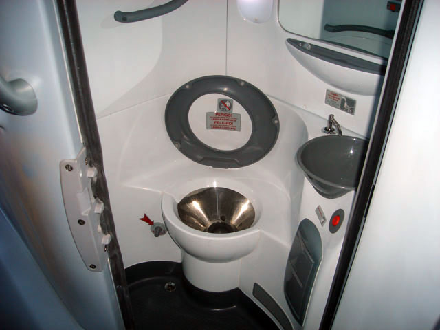 Banheiro no fundo do ônibus com privada, lavatório e espelho